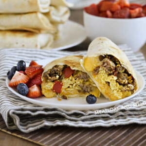 breakfast burritos made in the air fryer on a plate with strawberries and blueberries