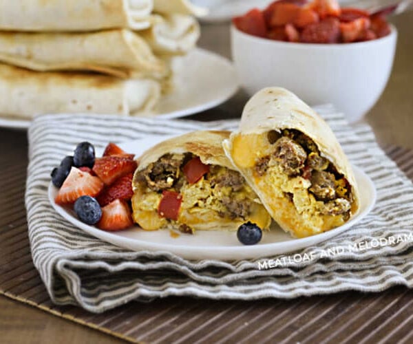 breakfast burritos made in the air fryer on a plate with strawberries and blueberries