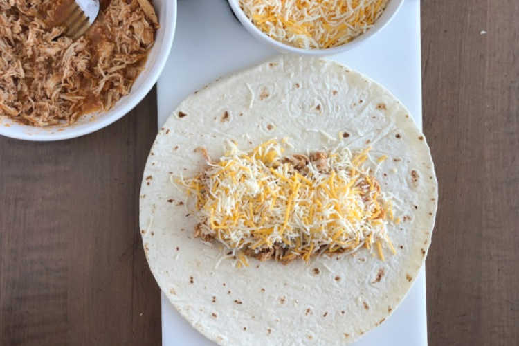 salsa chicken and shredded cheese on a tortilla