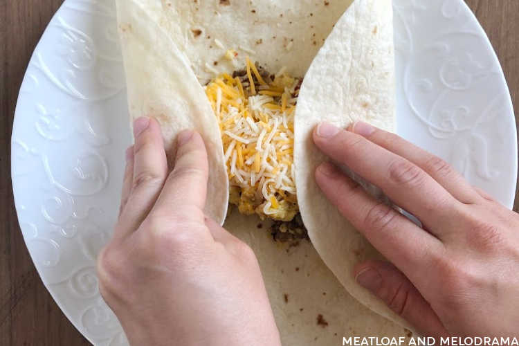 fold tortilla over scrambled eggs and sausage to make burrito