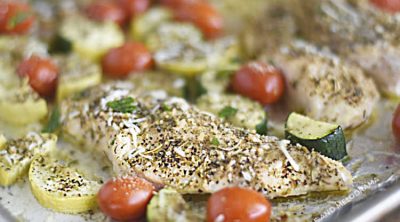 baked chicken with zucchini, yellow squash and grape tomatoes on a sheet pan