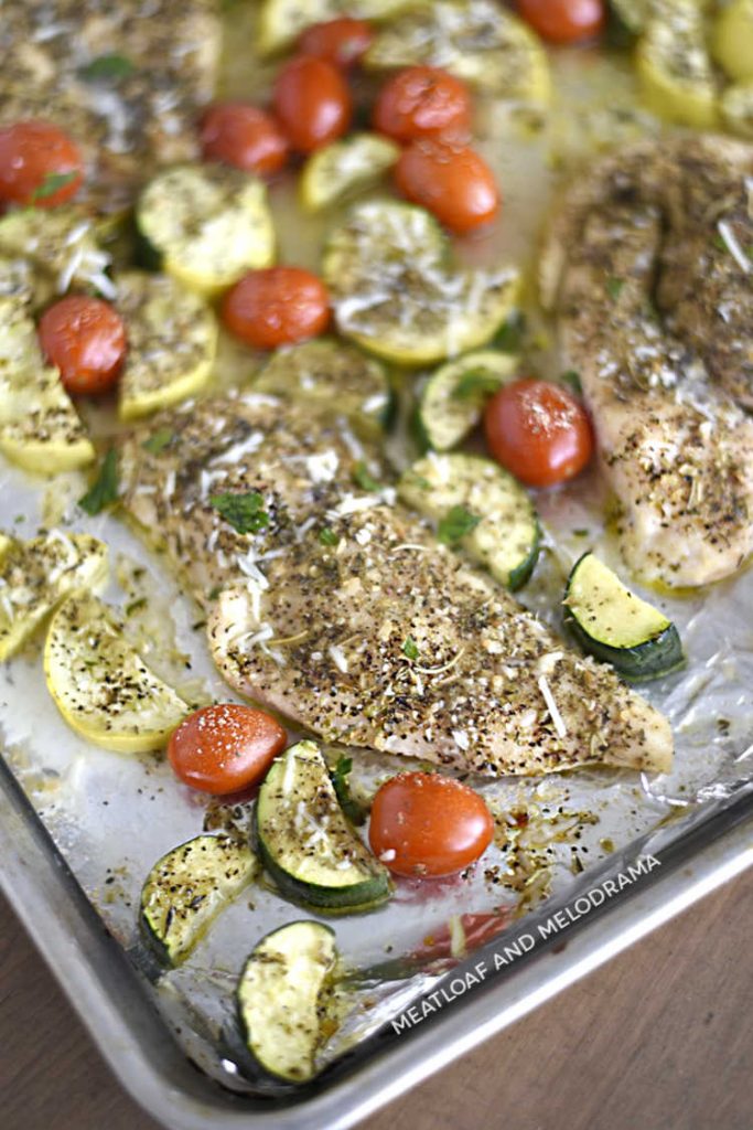 sheet pan with baked chicken breasts and summer vegetables