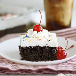 slice of chocolate root beer float cake with cool whip frosting and a cherry on top