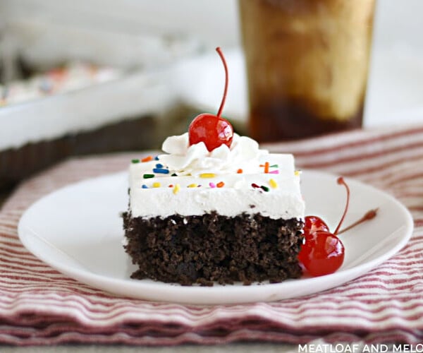 slice of chocolate root beer float cake with cool whip frosting and a cherry on top