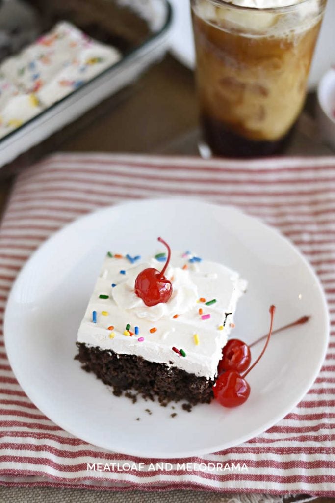 chocolate root beer float cake with cool whip and maraschino cherries on a plate
