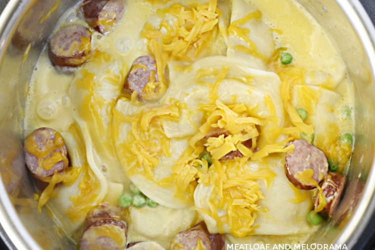 instant pot pierogi casserole with kielbasa, peas and shredded cheddar cheese in the pressure cooker