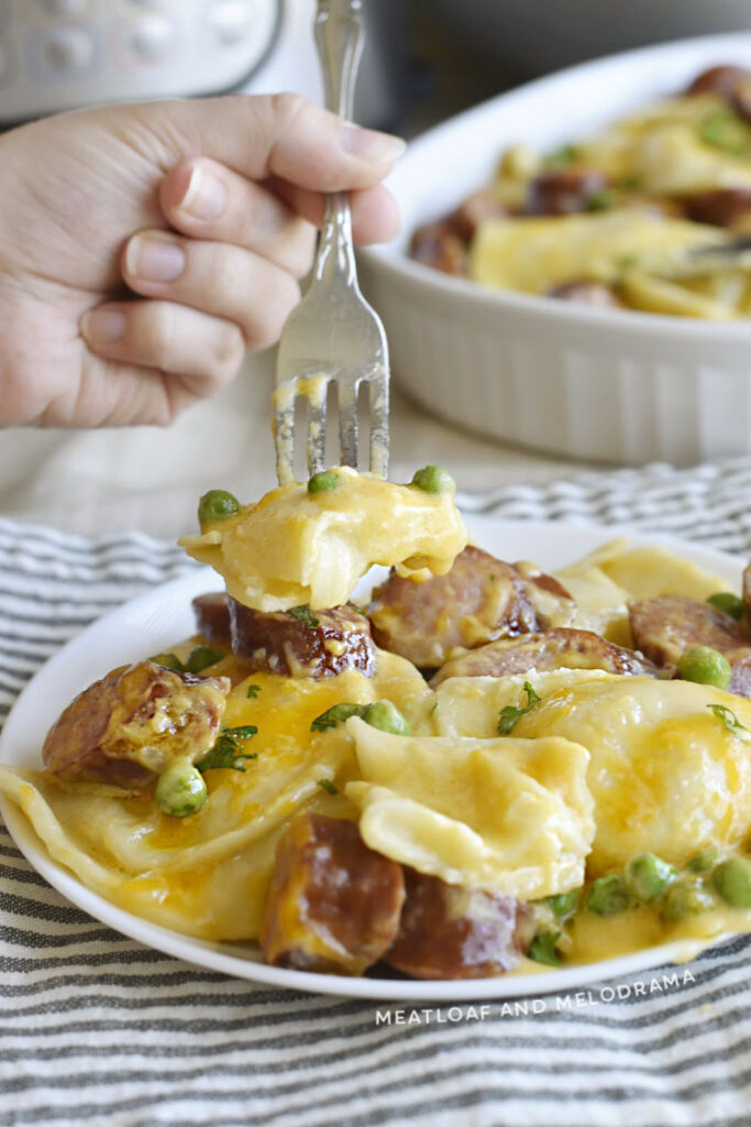potato pierogi in a creamy cheese sauce with peas and smoked sausage  on a fork