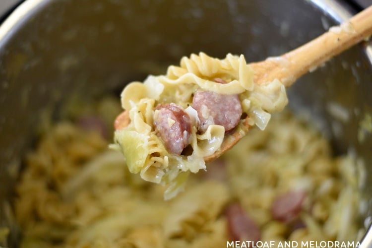 haluski cabbage noodles and kielbasa on wooden spoon