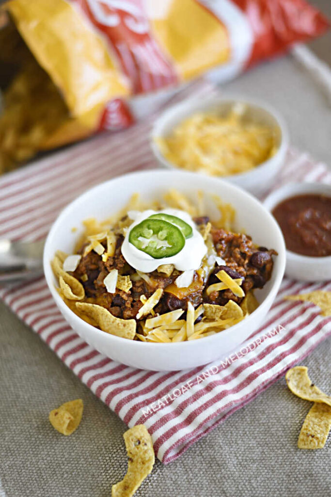 frito chili pie over corn chips in a bowl with bag of fritos