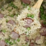 kielbasa with rice and peas on wooden spoon in the pressure cooker