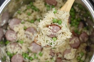 kielbasa with rice and peas on wooden spoon in the pressure cooker