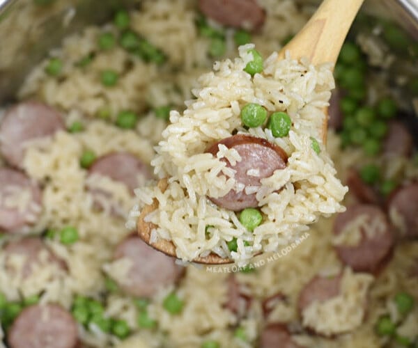 kielbasa with rice and peas on wooden spoon in the pressure cooker