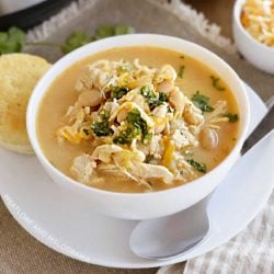 bowl of instant pot white chicken chili with white beans, corn and cheese and cilantro