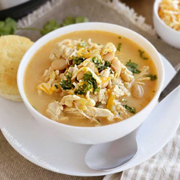 bowl of instant pot white chicken chili with white beans, corn and cheese and cilantro
