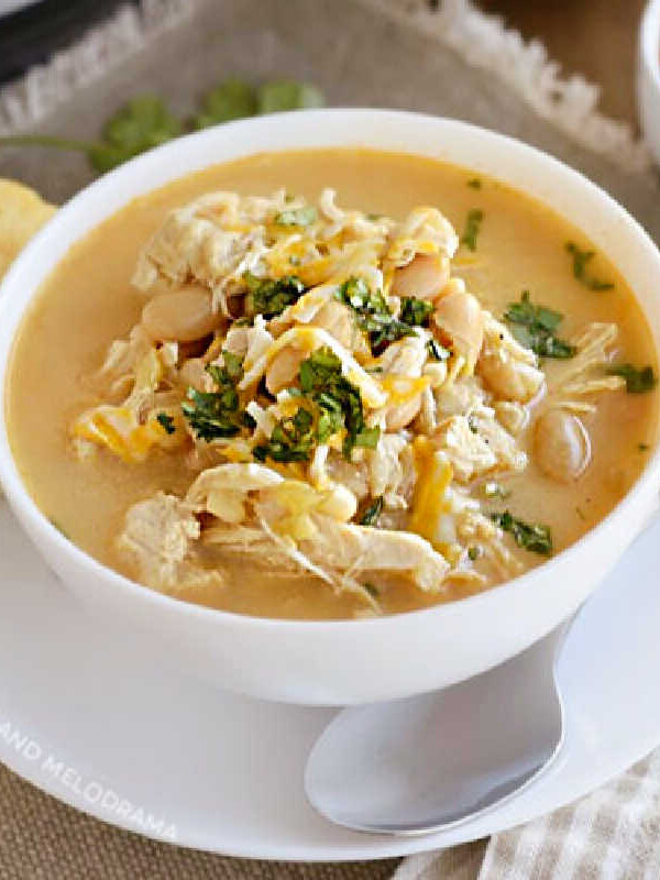 bowl of instant pot white chicken chili with white beans, corn and cheese and cilantro
