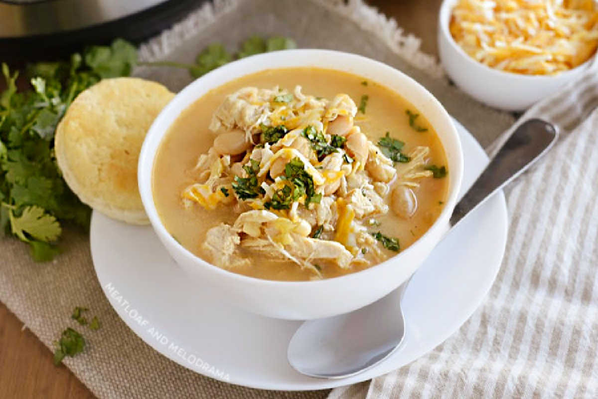 bowl of instant pot white chicken chili with white beans, corn and cheese and cilantro