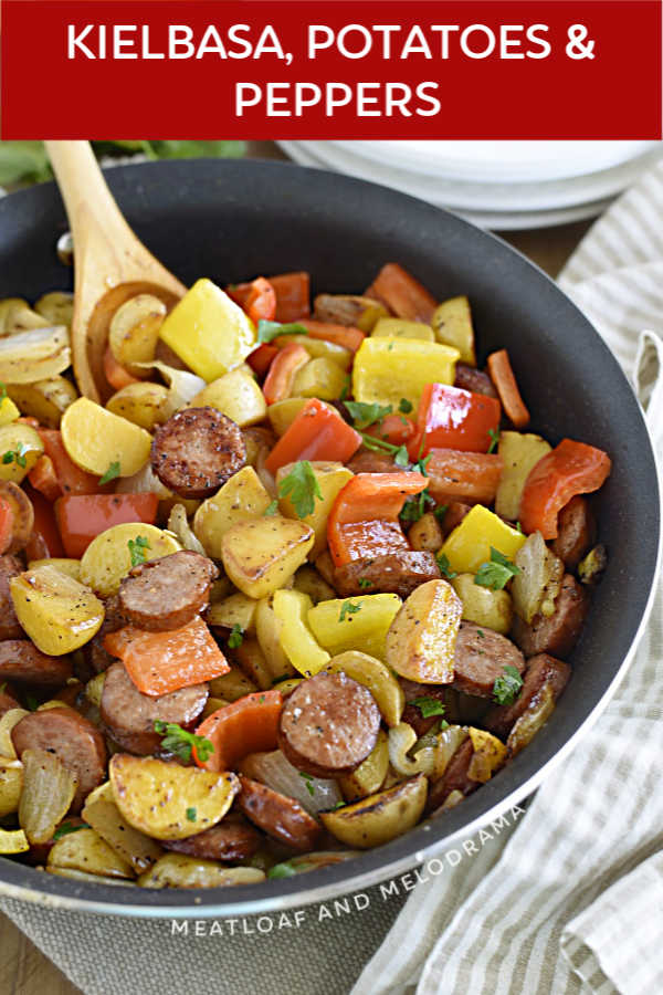 fried sliced kielbasa with cut baby potatoes, red bell peppers and onions in a skillet