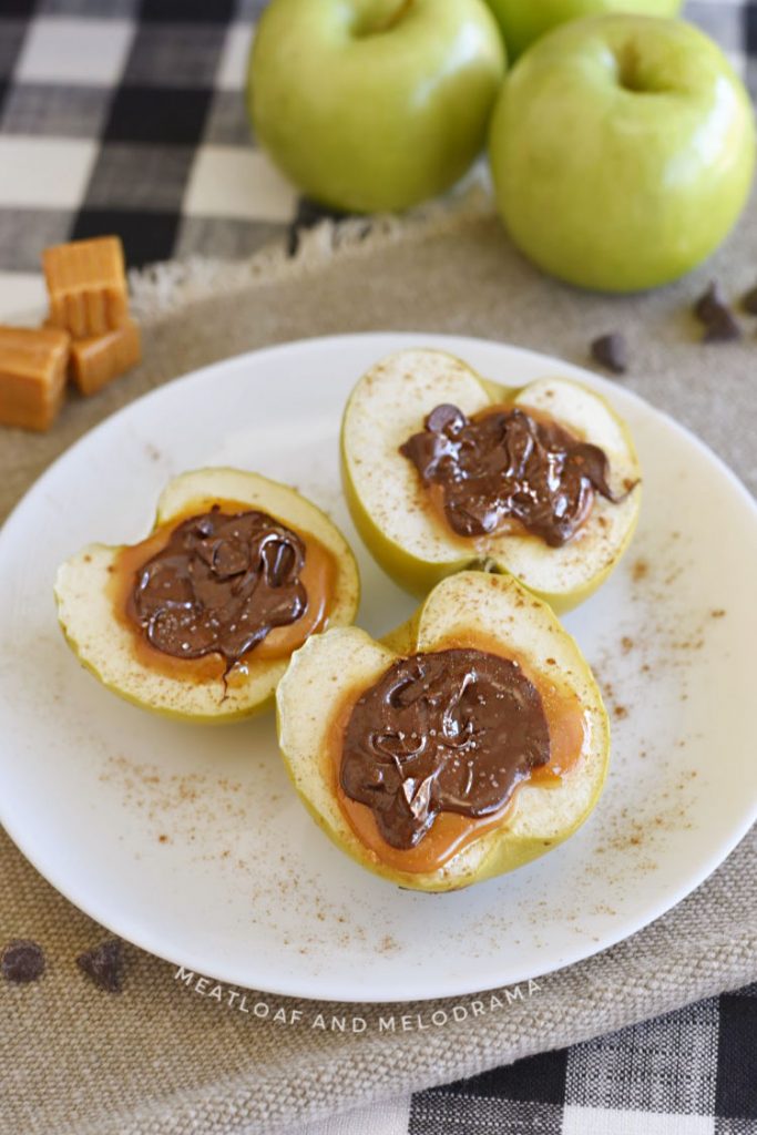 baked caramel apples topped with melted chocolate and sea salt on a white plate