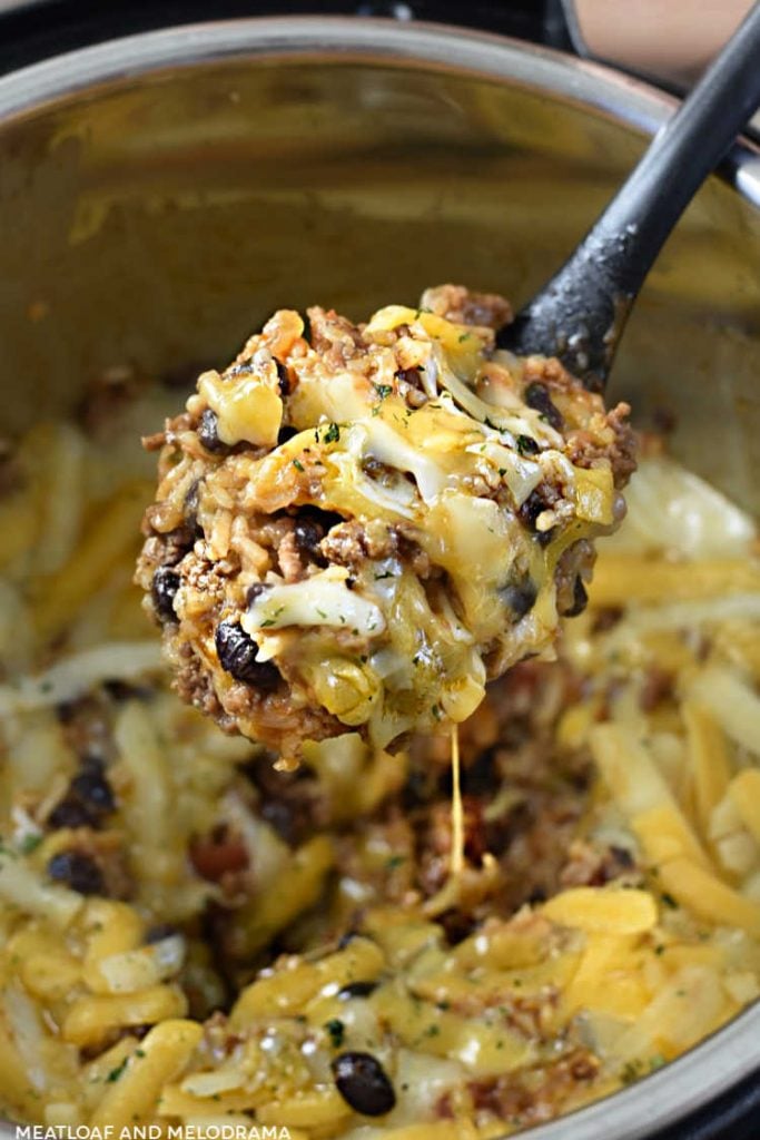 cheesy Mexican ground beef and rice with black beans on a serving spoon in the instant pot