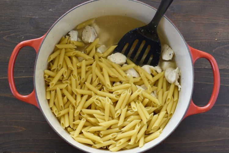 diced chicken breasts and uncooked penne pasta in large pot