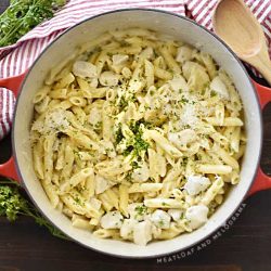 one pot chicken alfredo penne pasta in a red dutch oven with parsley