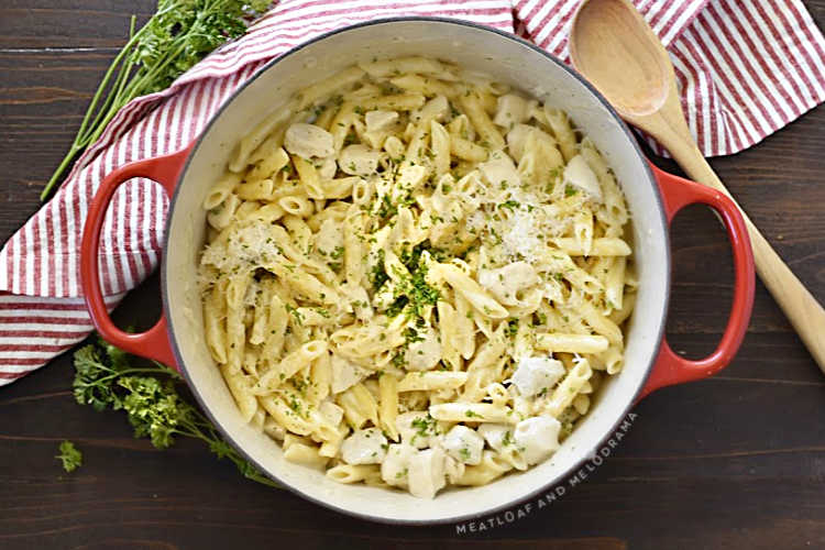 one pot chicken alfredo with penne pasta in a red dutch oven with parsley