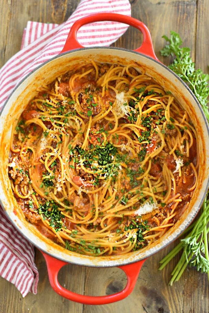 one-pot spaghetti and meat sauce with parsley flakes in a red dutch oven