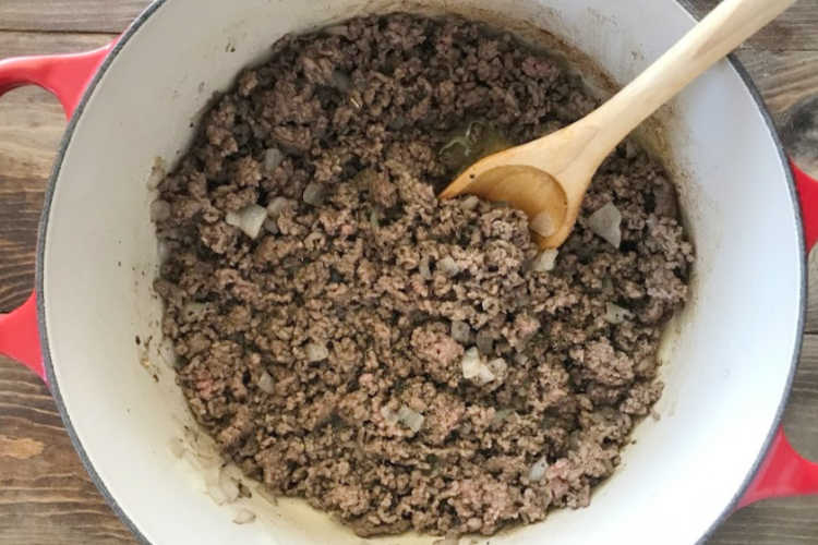 brown ground beef and onion in red dutch oven