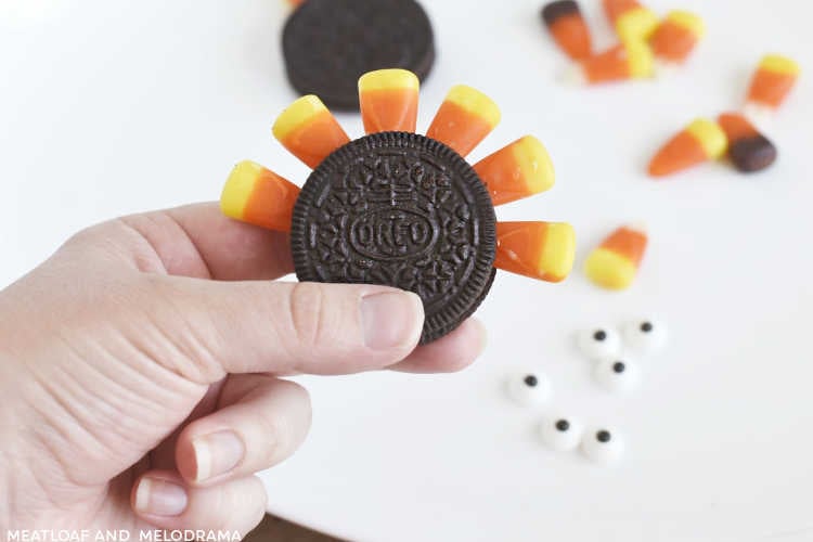 hand holding oreo cookie with candy corn in middle