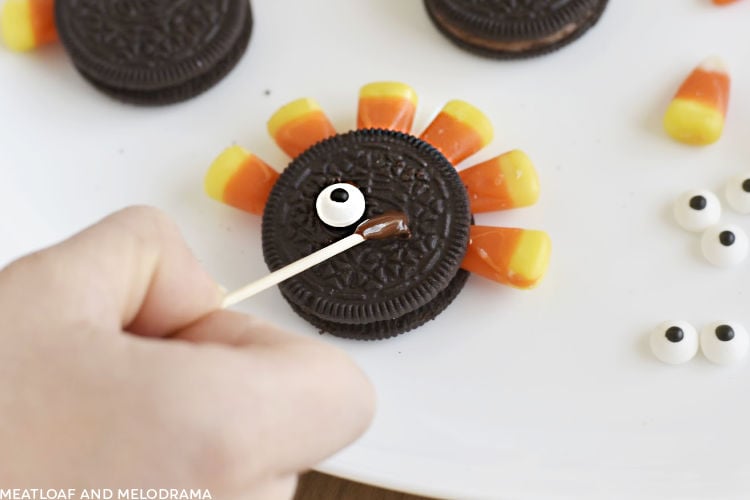 apply melted chocolate to oreo with toothpick to hold eye on oreo cookie turkeys