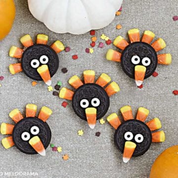turkey cookies made with oreos, candy corn and candy eyes on a brown placemat with pumpkins