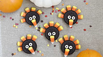 turkey cookies made with oreos, candy corn and candy eyes on a brown placemat with pumpkins