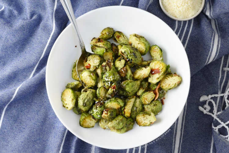bowl of brussels sprouts with parmesan and bacon on a blue cloth