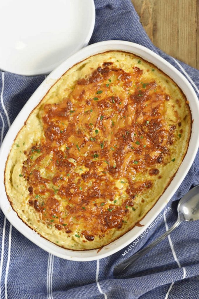 potatoes au gratin in a white baking dish topped with parsley