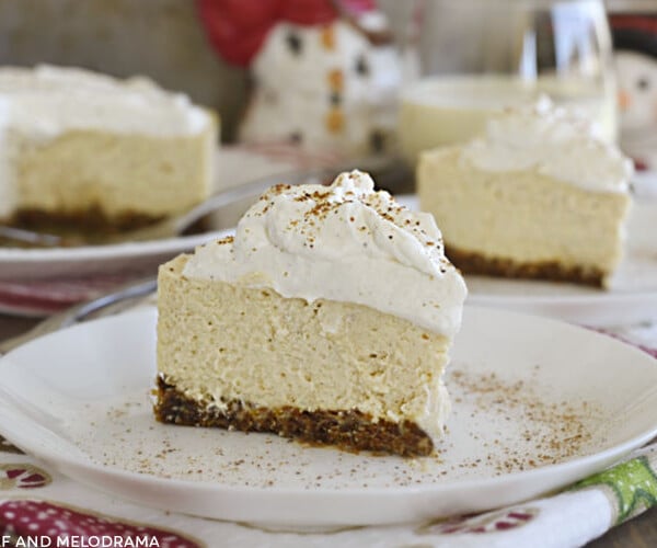 slice of instant pot eggnog cheesecake with eggnog whipped cream on a plate