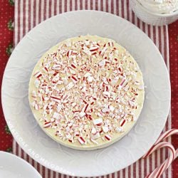 peppermint cheesecake topped with crushed candy canes on a white plate