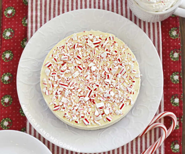 peppermint cheesecake topped with crushed candy canes on a white plate