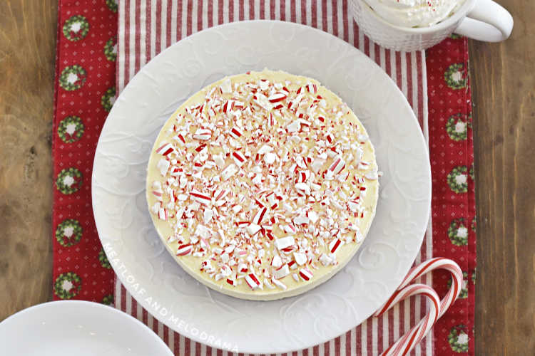 peppermint cheesecake topped with crushed candy canes on a white plate