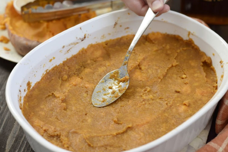 smooth mashed sweet potatoes in casserole dish with a spoon