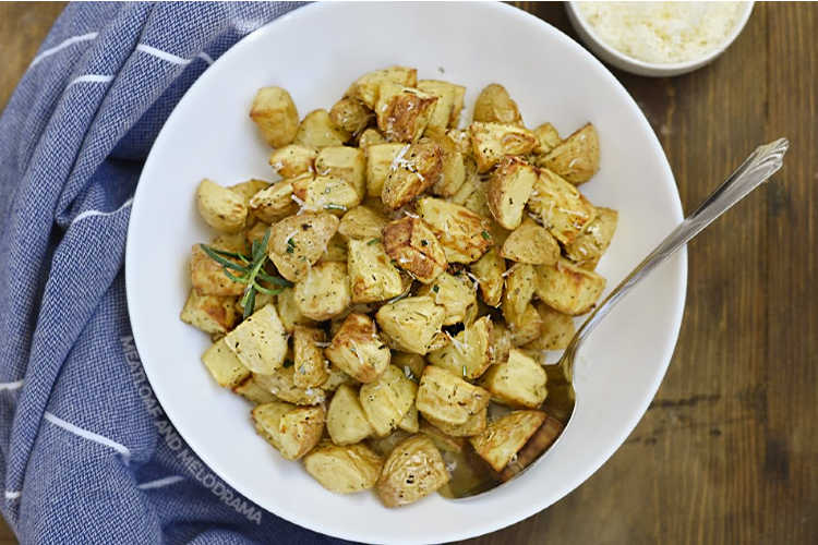 air fryer roasted potatoes with rosemary, garlic and grated Parmesan in a white serving bowl