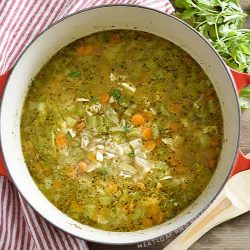 turkey soup with rice, celery and carrots and in a red dutch oven