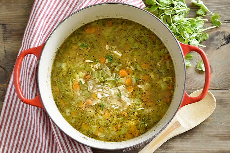 turkey soup with rice, celery and carrots and in a red dutch oven