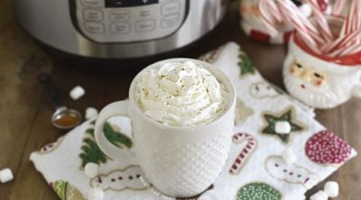cup of hot chocolate with whipped cream in front of an instant pot