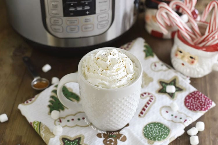 cup of hot chocolate with whipped cream in front of an instant pot