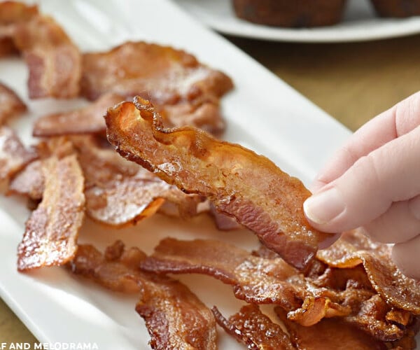 hand holding slice of crispy bacon