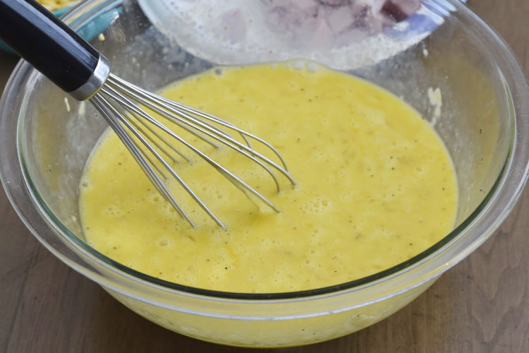 scramble eggs with whisk in a glass mixing bowl