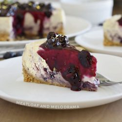 slice of lemon blueberry cheesecake with blueberry sauce on top and sides