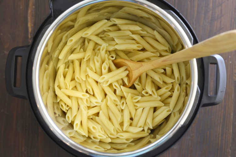 wooden spoon in instant pot with penne pasta