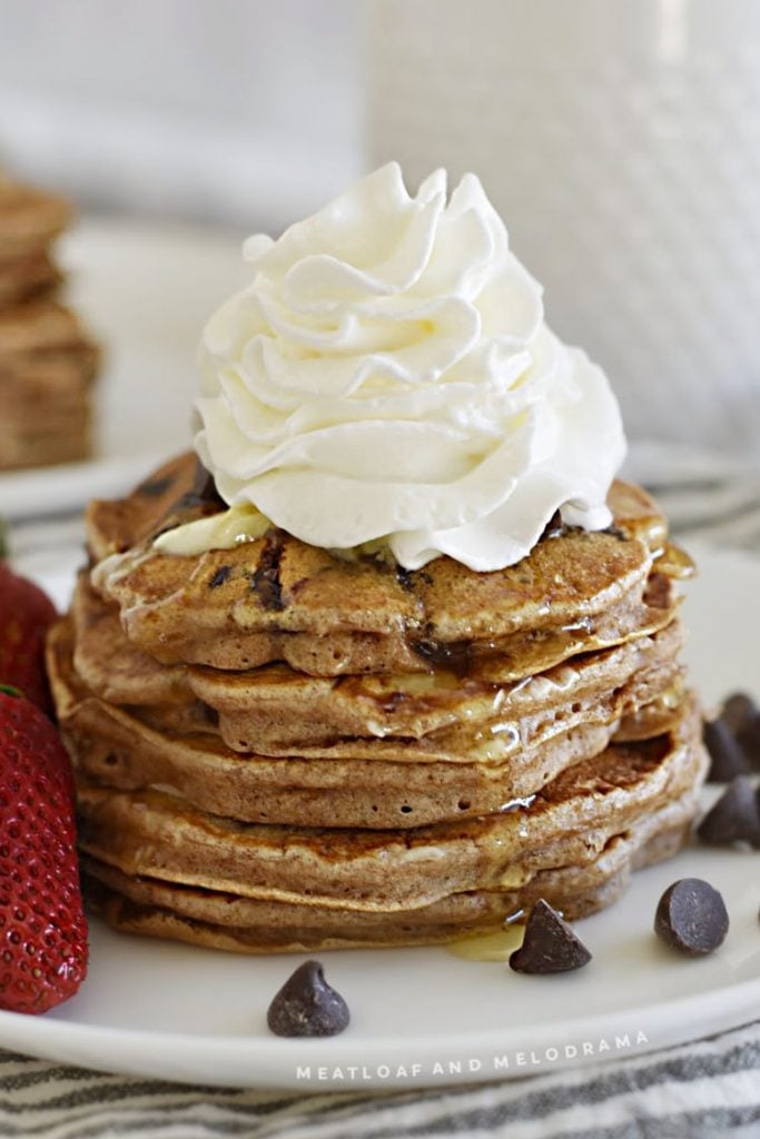 stack of pancakes with chocolate morsels and whipped cream
