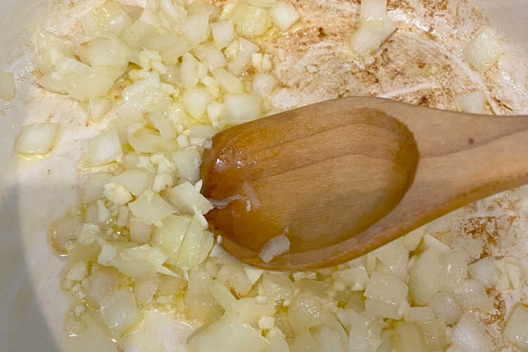  chopped onions and garlic with wooden spoon in dutch oven